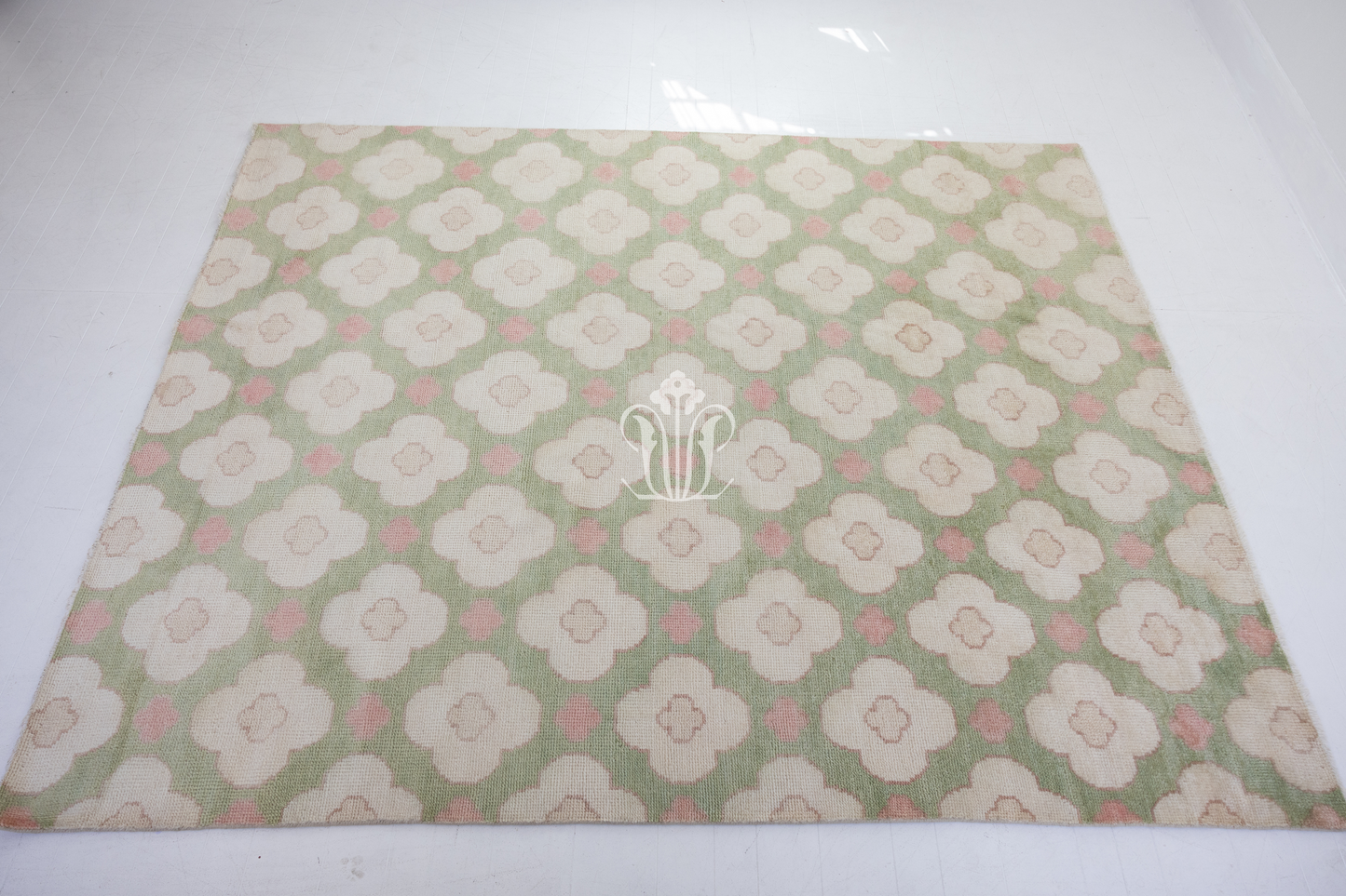 Pattern of white flowers with pink centers on a green background on a handknotted rug