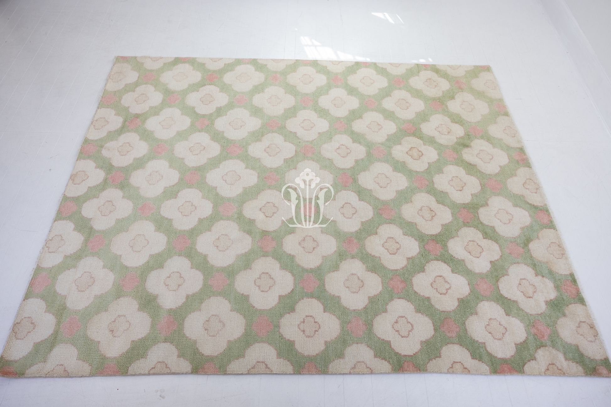Pattern of white flowers with pink centers on a green background on a handknotted rug
