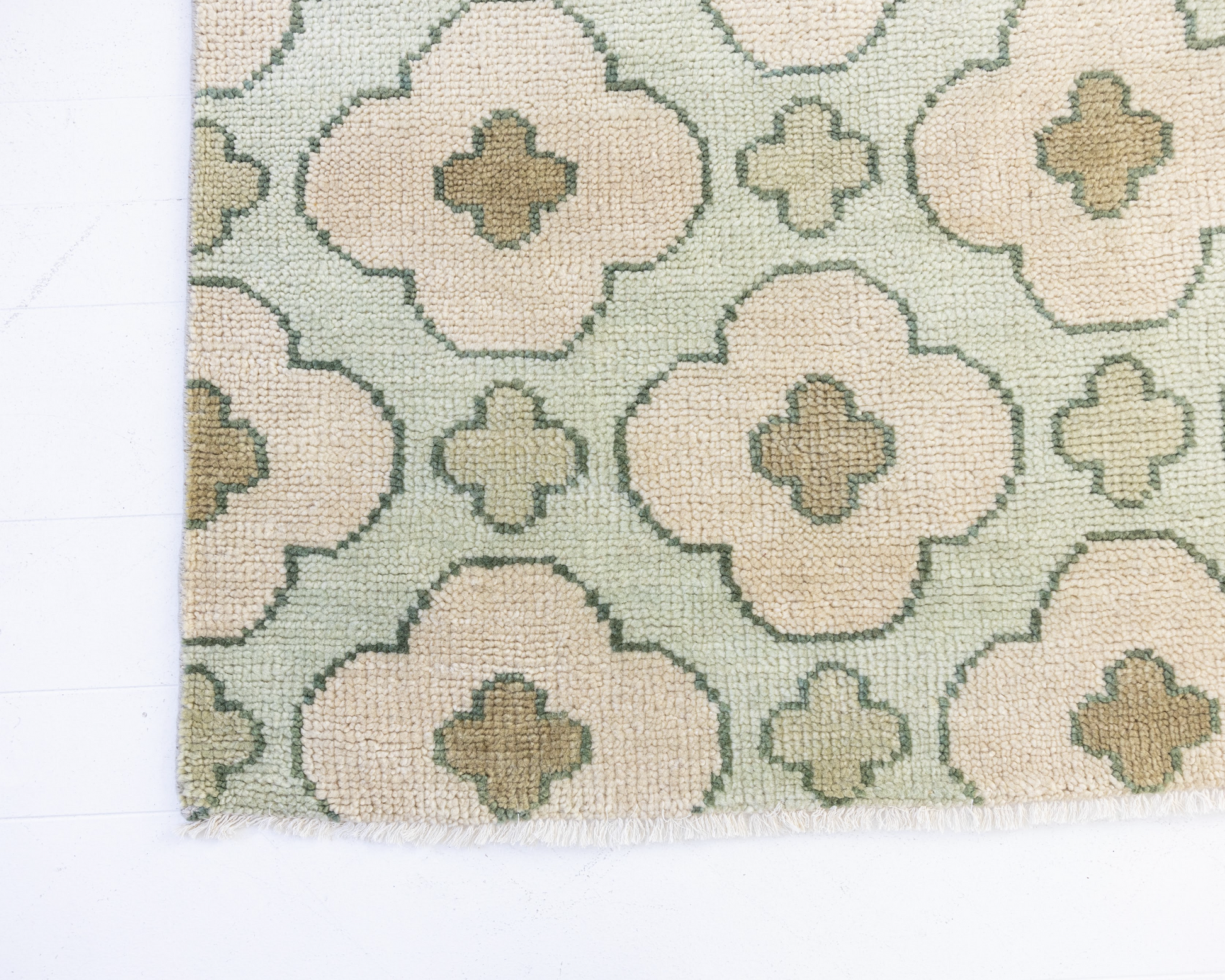 Patterned handknotted rug with geometric floral design on a light blue background