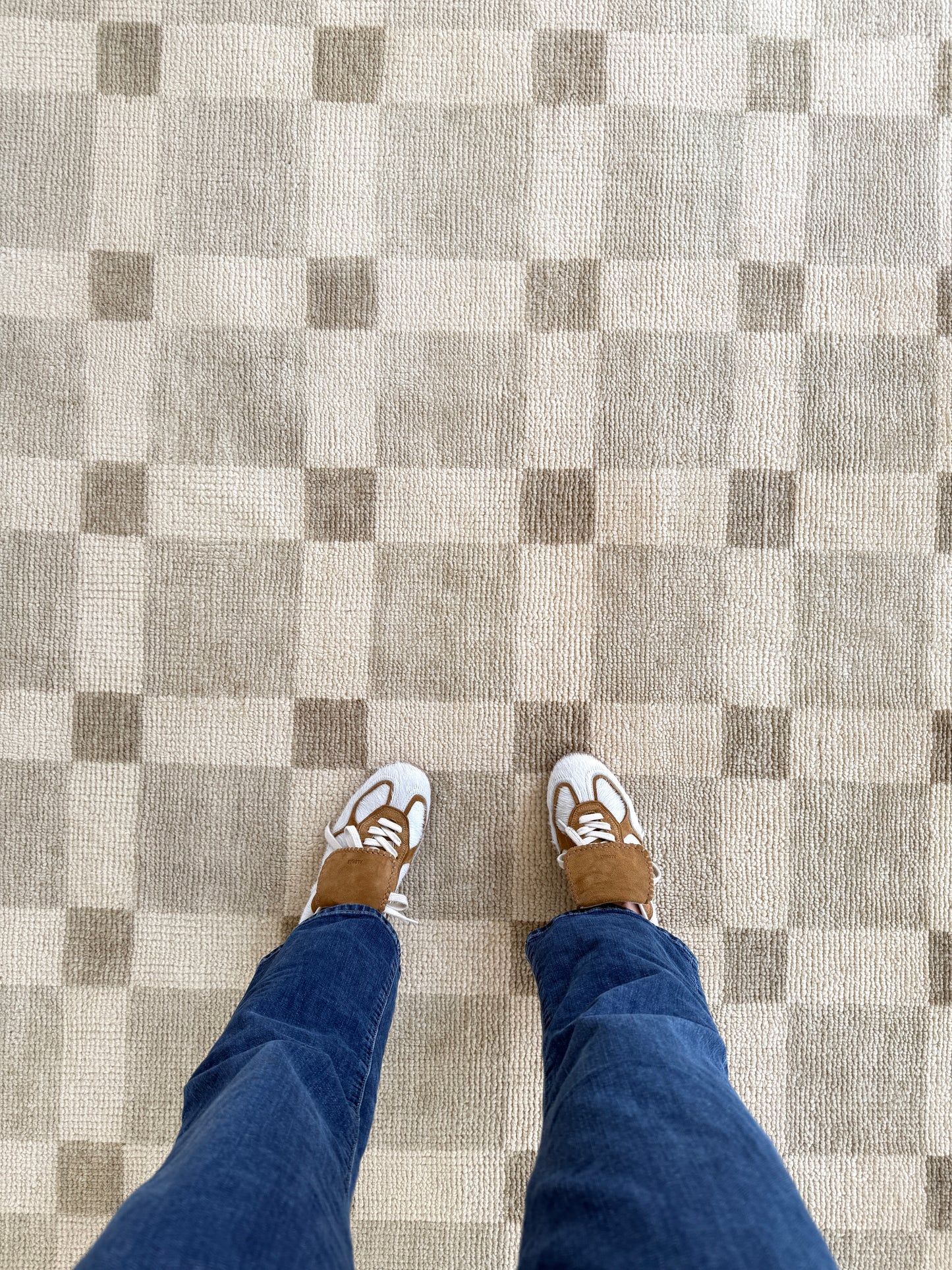 Checkered floor with a person wearing blue jeans and white sneakers.
