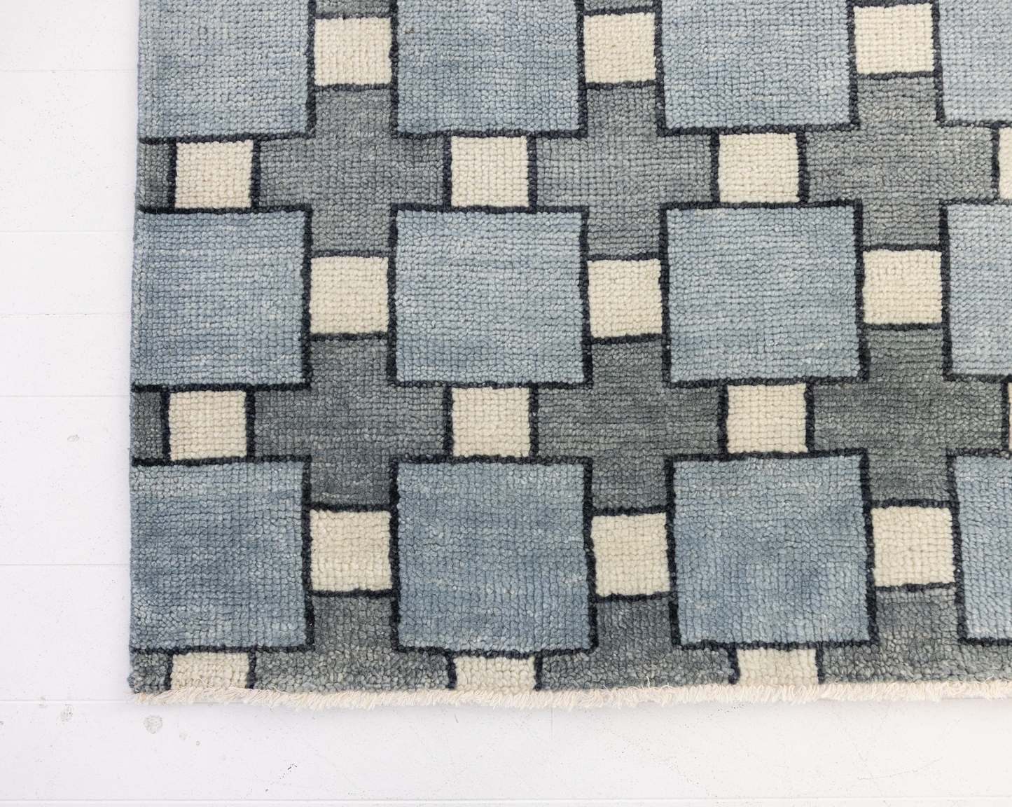 Geometric patterned rug with blue and beige squares on a white background