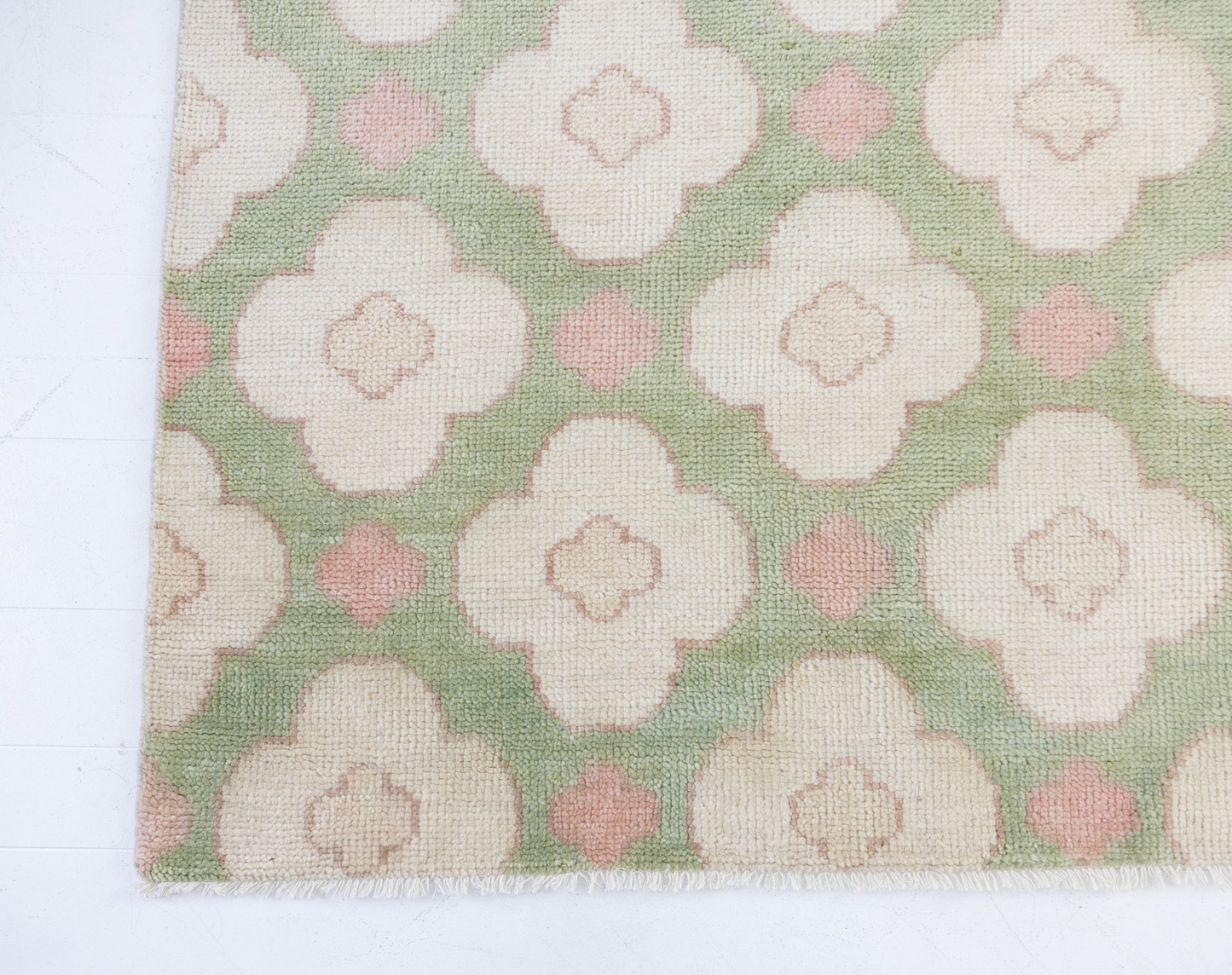 Pattern of white flowers with pink centers on a green background on a handknotted rug