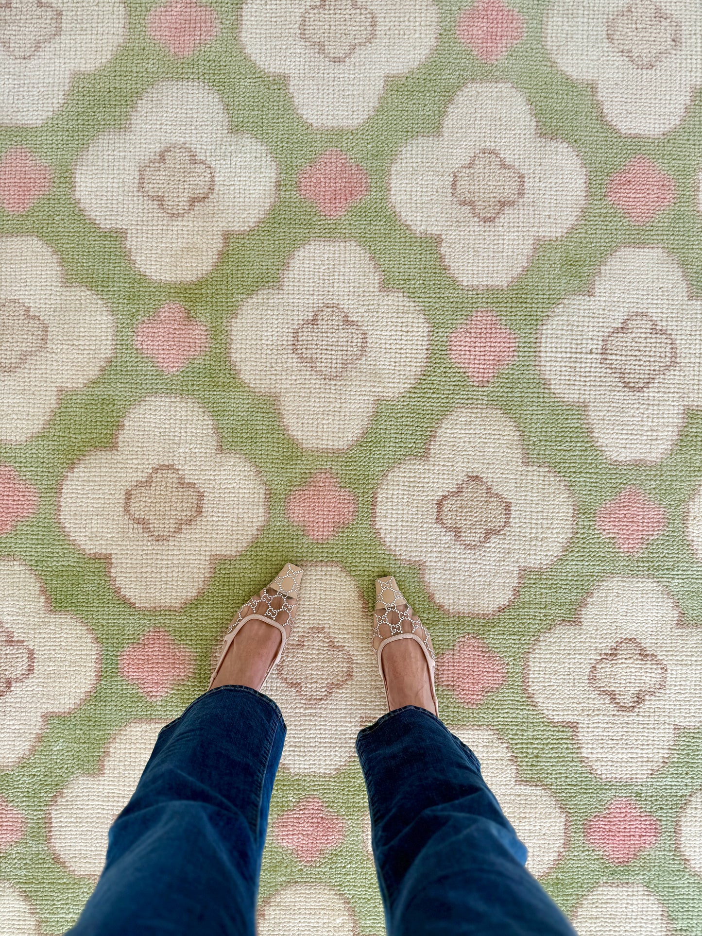Pattern of white flowers with pink centers on a green background on a handknotted rug