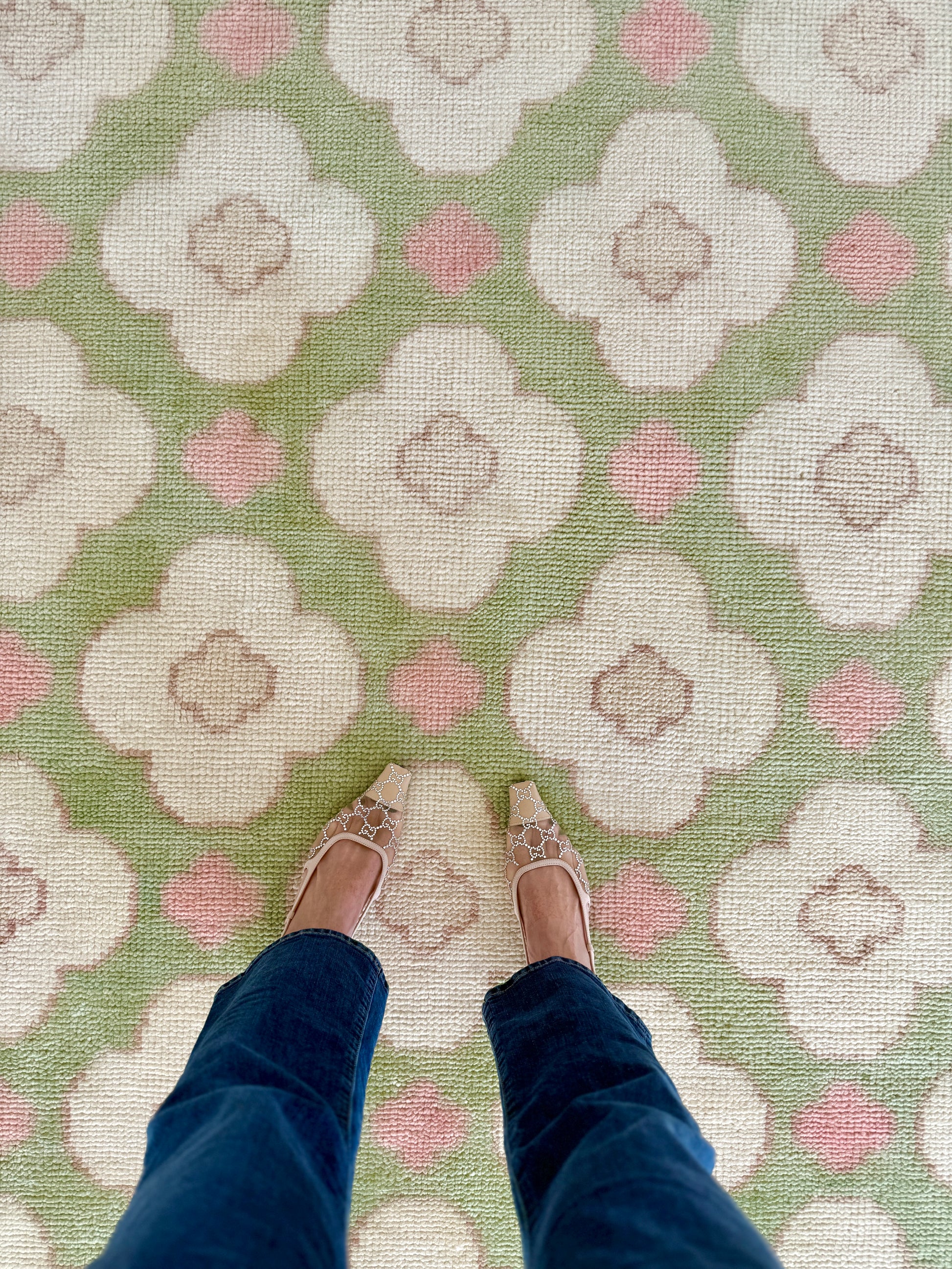 Pattern of white flowers with pink centers on a green background on a handknotted rug