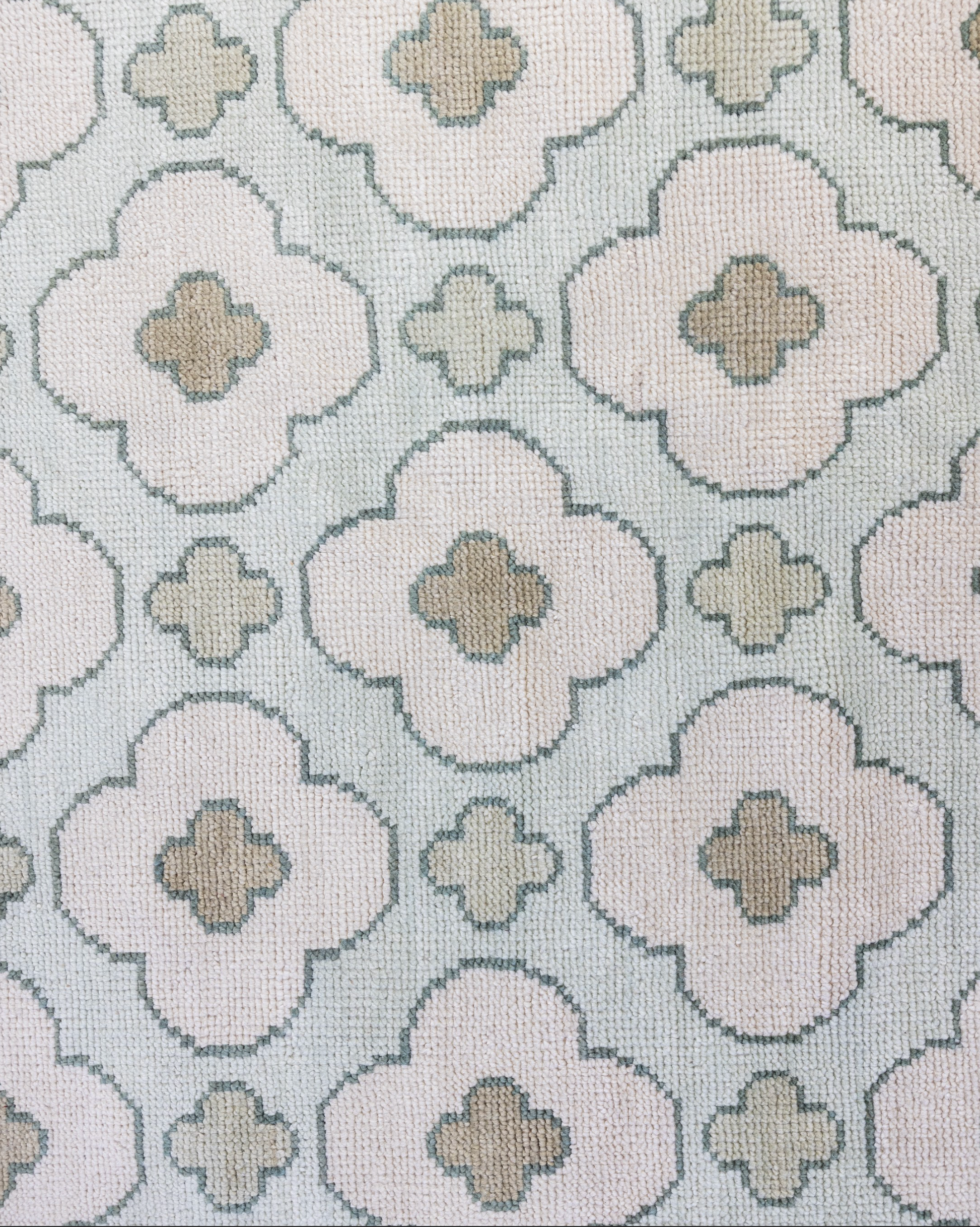 Patterned handknotted rug with geometric floral design on a light blue background