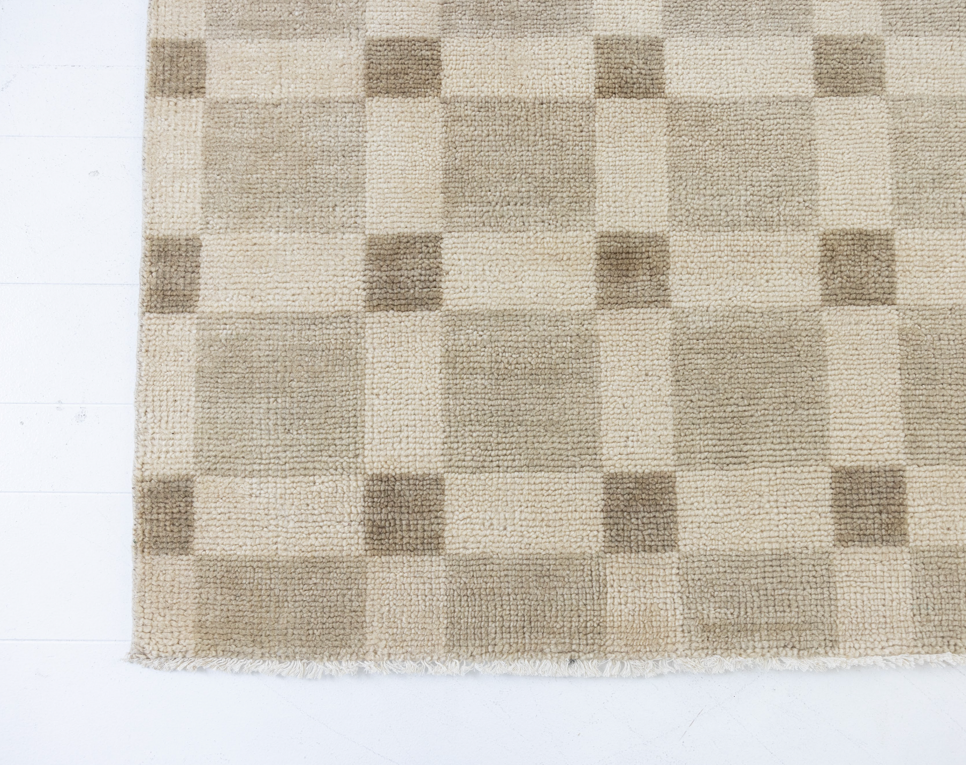 Checkered rug with brown and beige squares on a white background