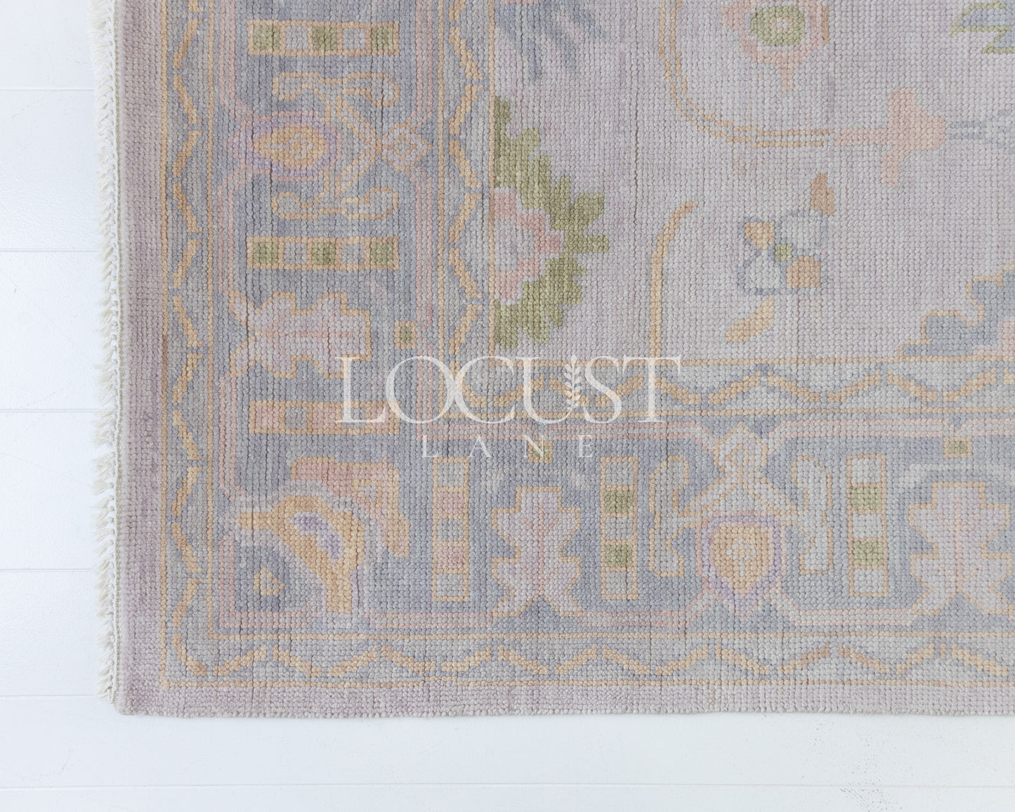 Hand-knotted wool rug in soft lavender and blush tones with sage and peach accents. The Rose Rug from Locust Lane features a delicate floral-inspired pattern that blends modern pastel hues with timeless craftsmanship.
