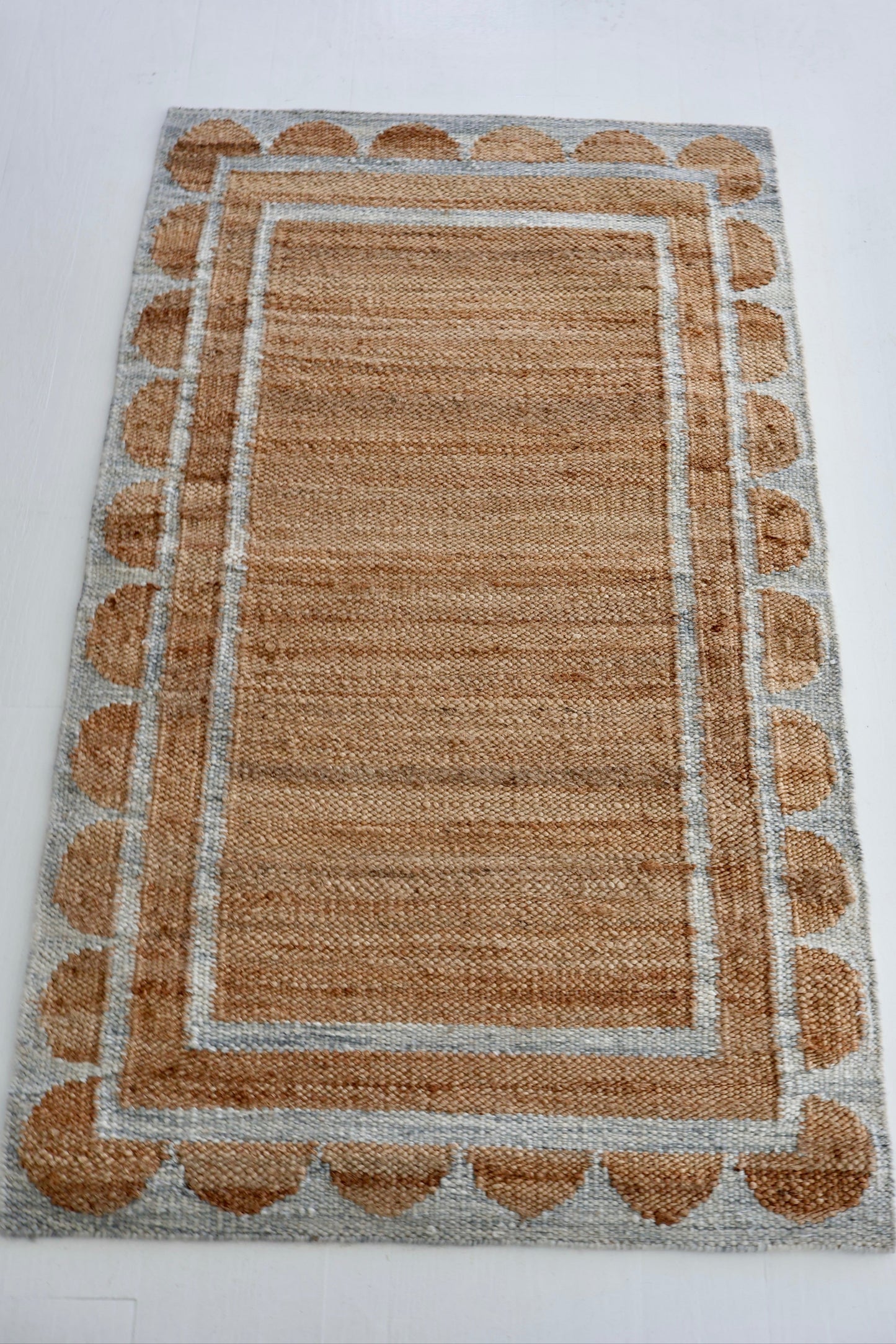 Handwoven jute and wool rug in natural tones with a stone-blue scalloped border – Stone Blue Scalloped Edge Rug by Locust Lane Rugs