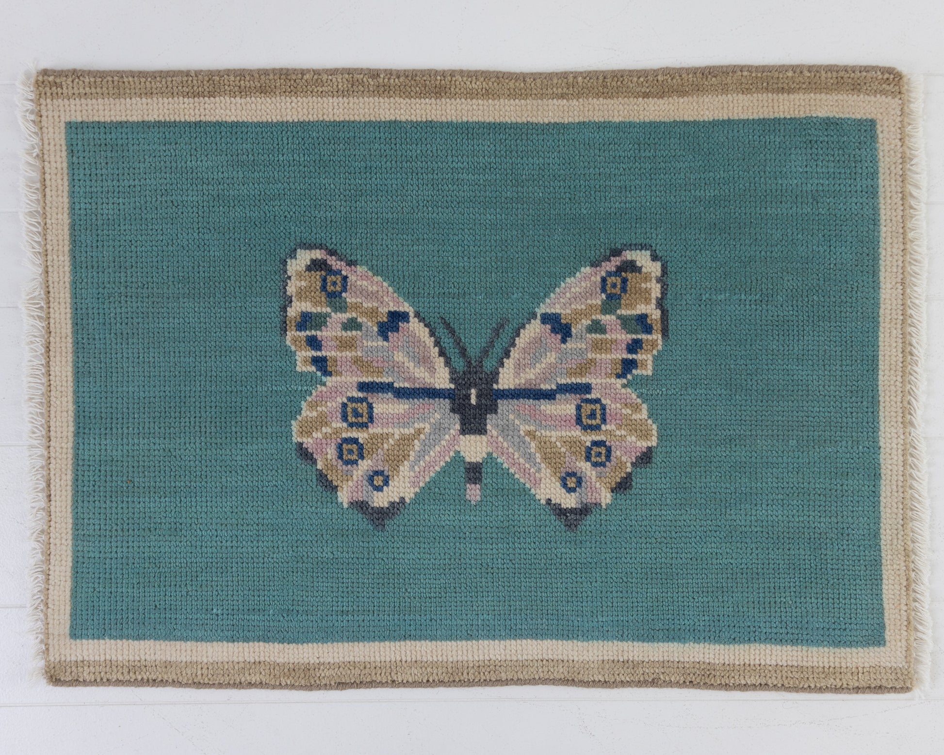 Hand-knotted wool rug featuring a butterfly motif on a turquoise background with ivory border – Turquoise Butterfly Mini Rug by Locust Lane Rugs