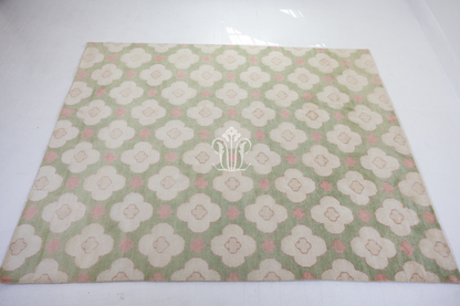 Pattern of white flowers with pink centers on a green background on a handknotted rug