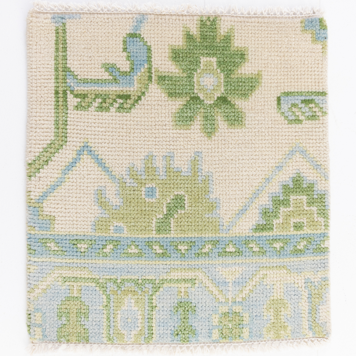 A square woven textile swatch with a cream base and a geometric floral pattern in light green, pale blue, and touches of white, shown against a plain white background.