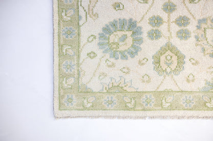 Essie traditional Oushak rug showcasing a decorative floral border in pale blue, sage green, and warm ivory.
