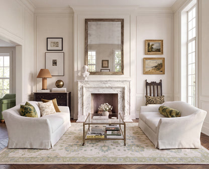 Essie blue and green Oushak area rug styled in a traditional living room with ivory sofas and classic furnishings.