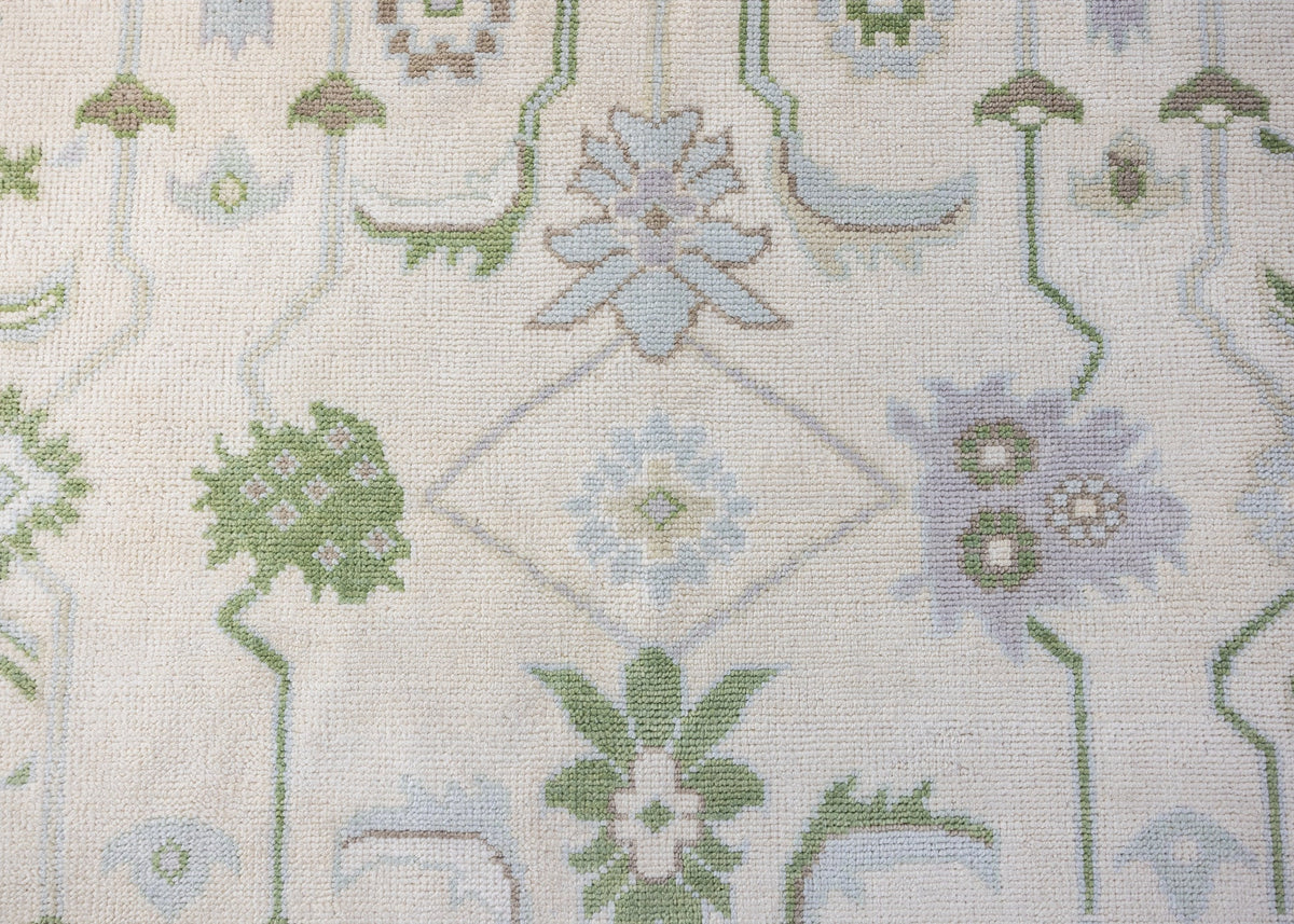 Fern hand-knotted wool Modern Oushak rug featuring botanical florals in soft blue, leafy green, and lavender on an ivory background.