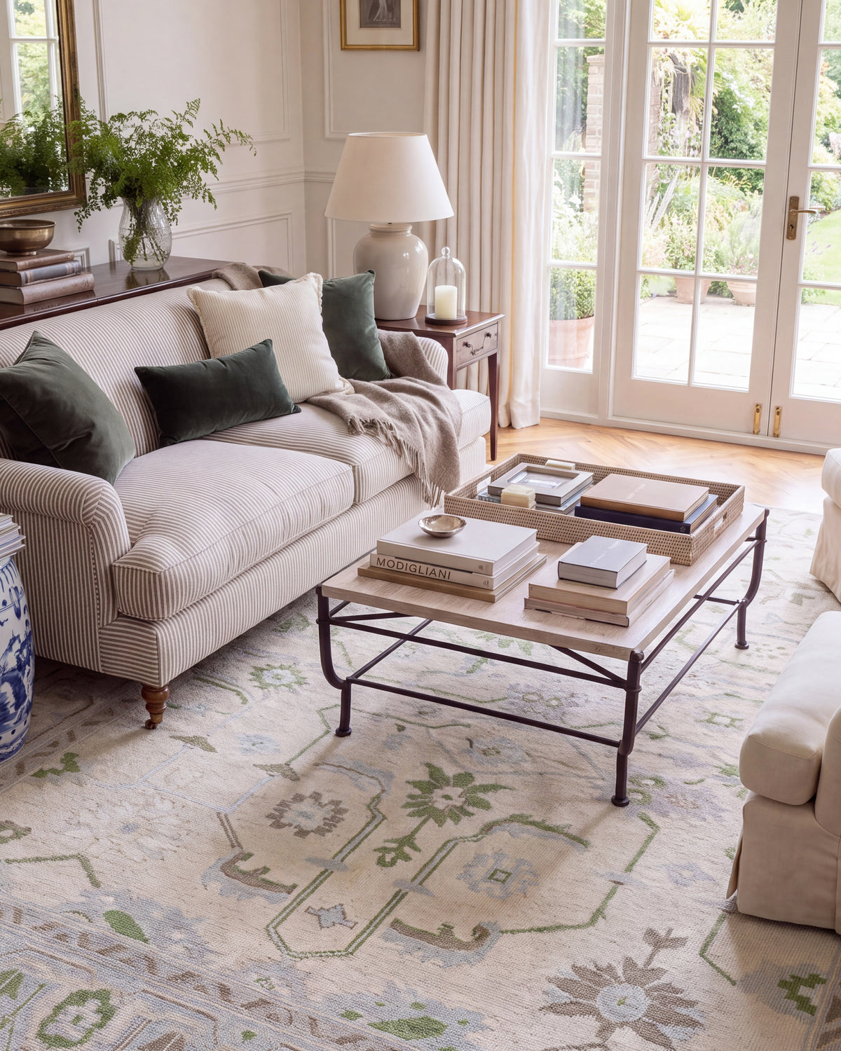 Fern hand-knotted floral area rug with soft green vines, powder blue flowers, and lavender accents styled beside a neutral sofa.