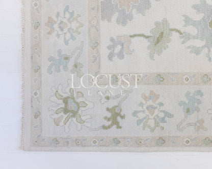 cream hand knotted rug with blues and greens