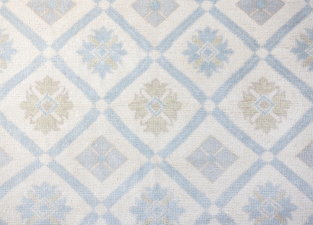 Pippa hand-knotted wool Modern Oushak rug featuring a powder blue and ivory diamond pattern with delicate floral motifs and soft beige accents.