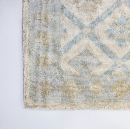 Pippa Modern Oushak rug featuring a decorative border and soft blue, ivory, and beige geometric motifs in hand-knotted wool.