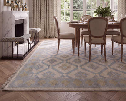 Pippa blue geometric Oushak rug featuring a diamond and floral pattern beneath a wooden dining table and upholstered chairs.