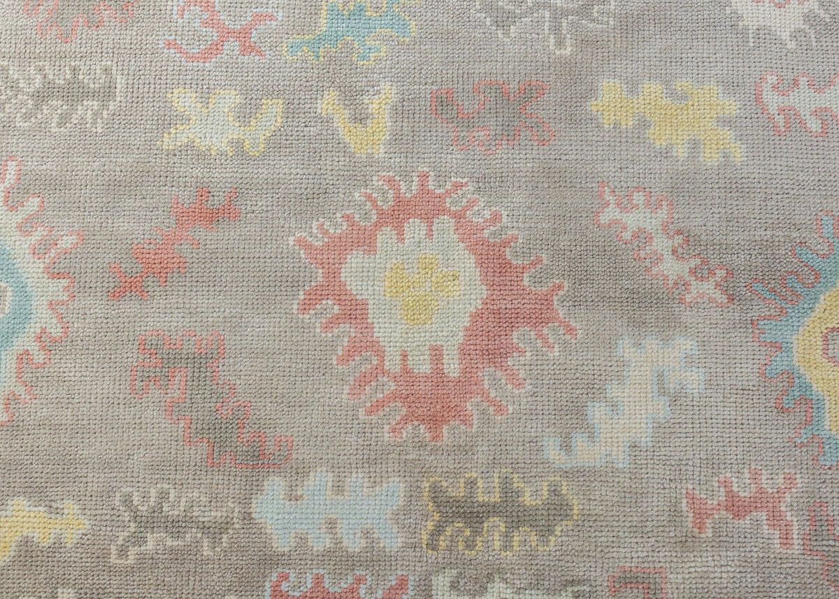 Sookie hand-knotted wool Modern Oushak rug featuring colorful floral motifs in coral pink, turquoise, buttery yellow, and pale blue on taupe.
