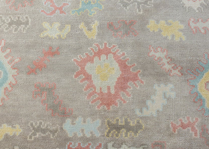 Sookie hand-knotted wool Modern Oushak rug featuring colorful floral motifs in coral pink, turquoise, buttery yellow, and pale blue on taupe.