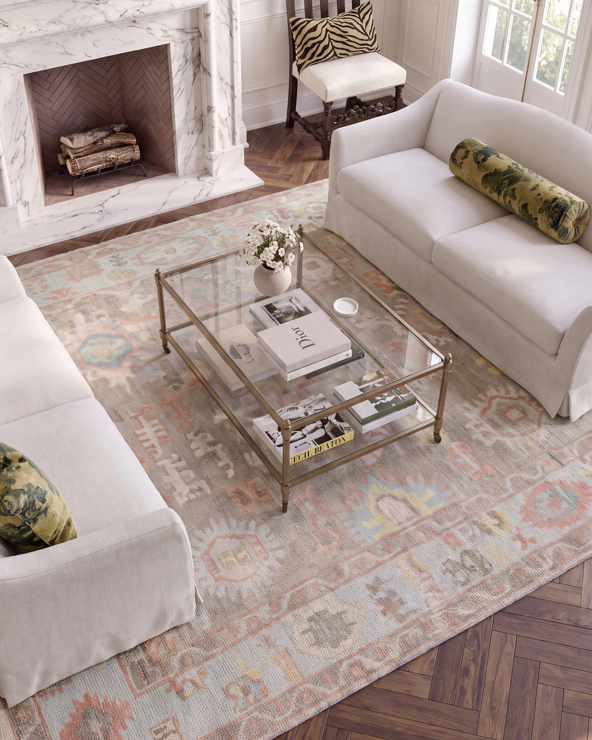 Sookie hand-knotted wool Oushak rug featuring coral pink, turquoise, and yellow floral patterns beneath a glass coffee table.