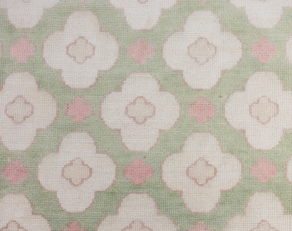 Pattern of white flowers with pink centers on a green background on a handknotted rug