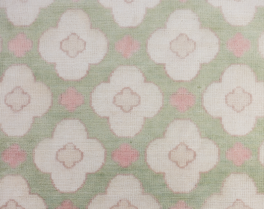 Pattern of white flowers with pink centers on a green background on a handknotted rug