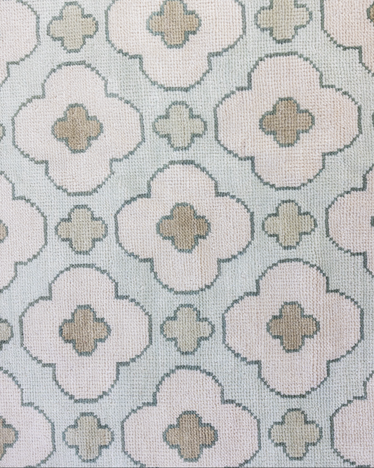 Patterned handknotted rug with geometric floral design on a light blue background