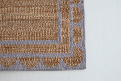 Jute and wool rug with lilac scalloped edge, handwoven for natural elegance.