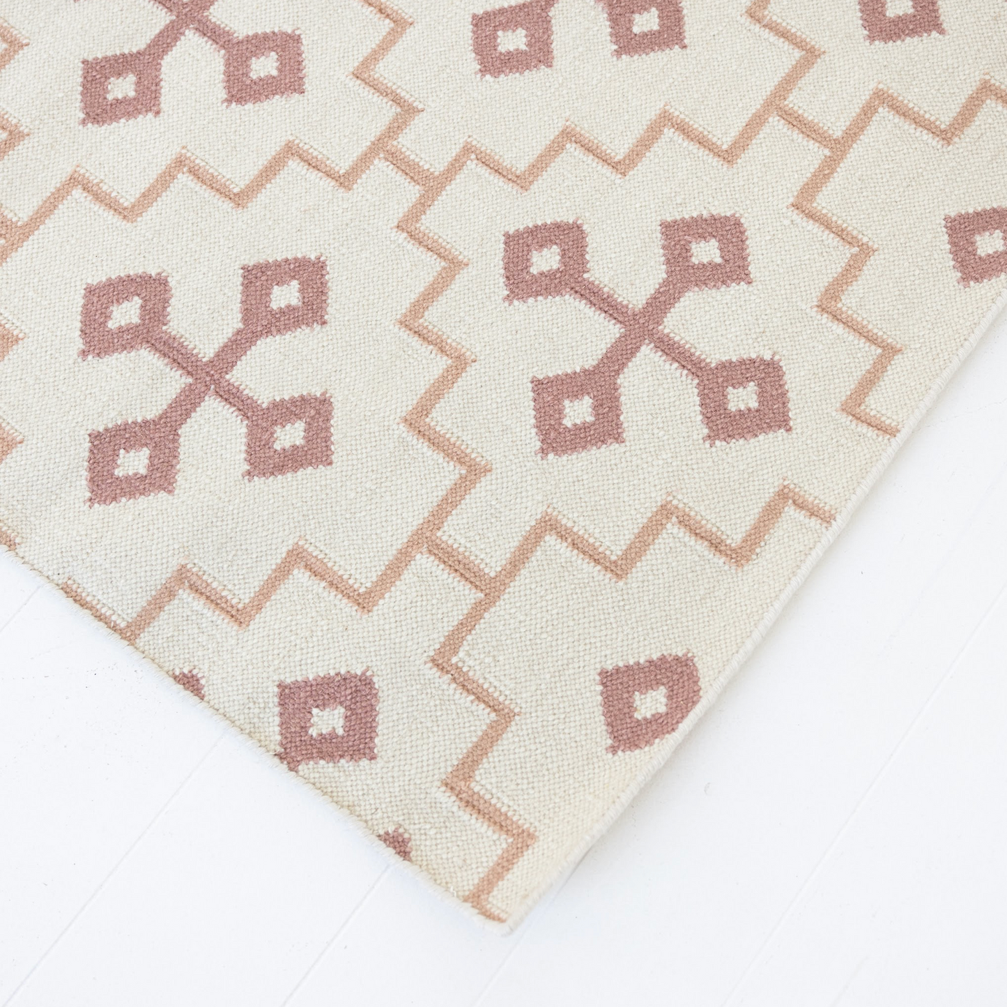 Close-up of the French Rose Flatweave Rug featuring dusty rose geometric motifs on an ivory background.