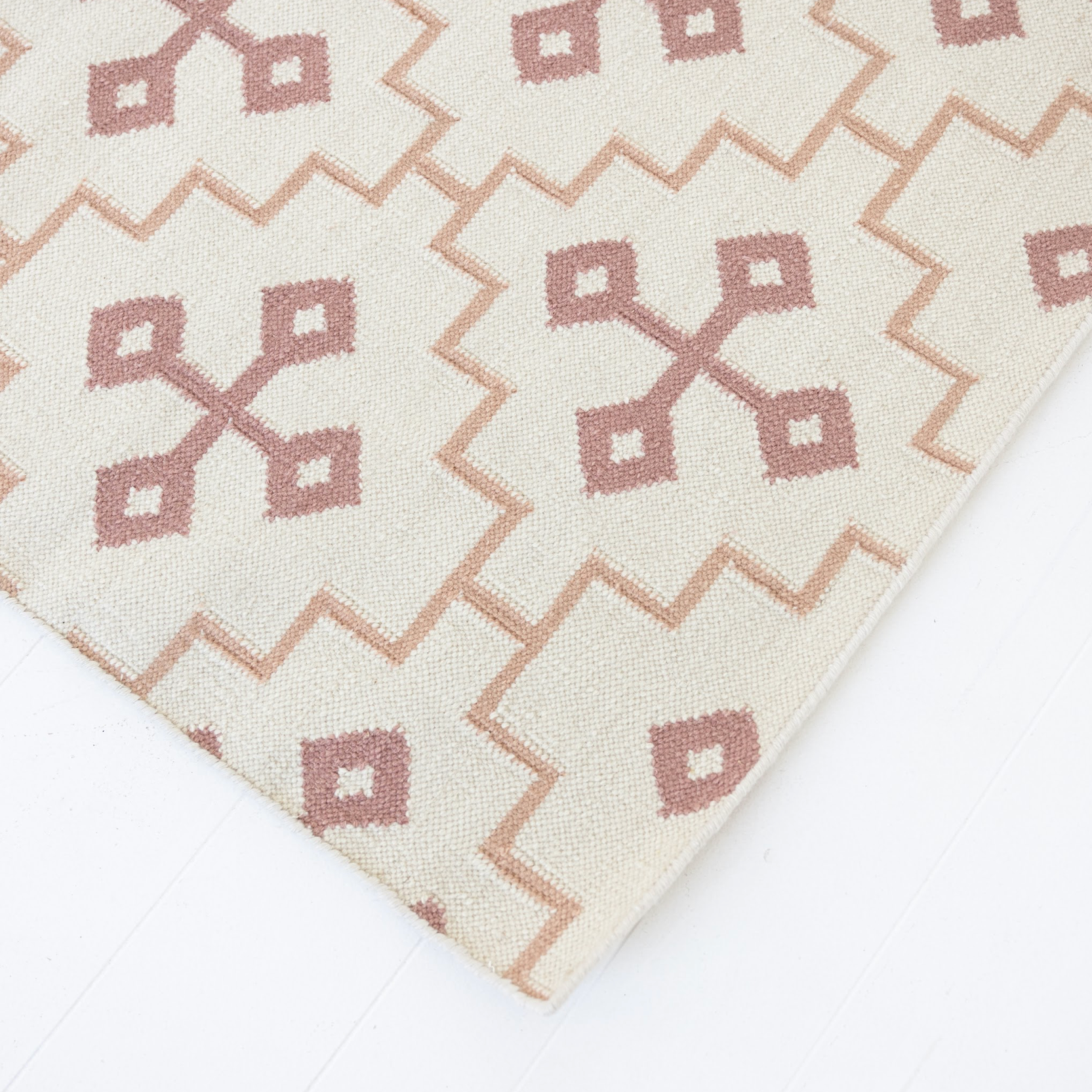 Close-up of the French Rose Flatweave Rug featuring dusty rose geometric motifs on an ivory background.