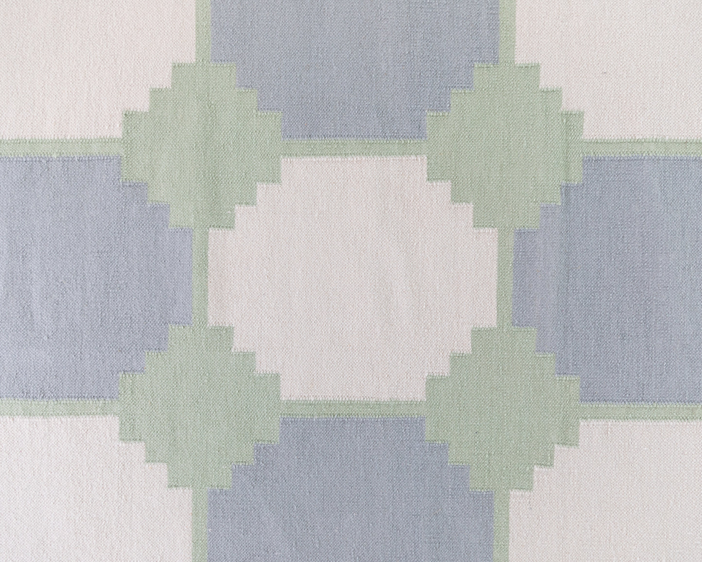 Close-up of the Geometric Flatweave Rug featuring oversized blue and sage geometric motifs on an ivory background.