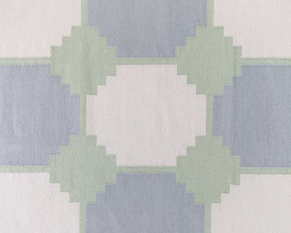 Close-up of the Geometric Flatweave Rug featuring oversized blue and sage geometric motifs on an ivory background.