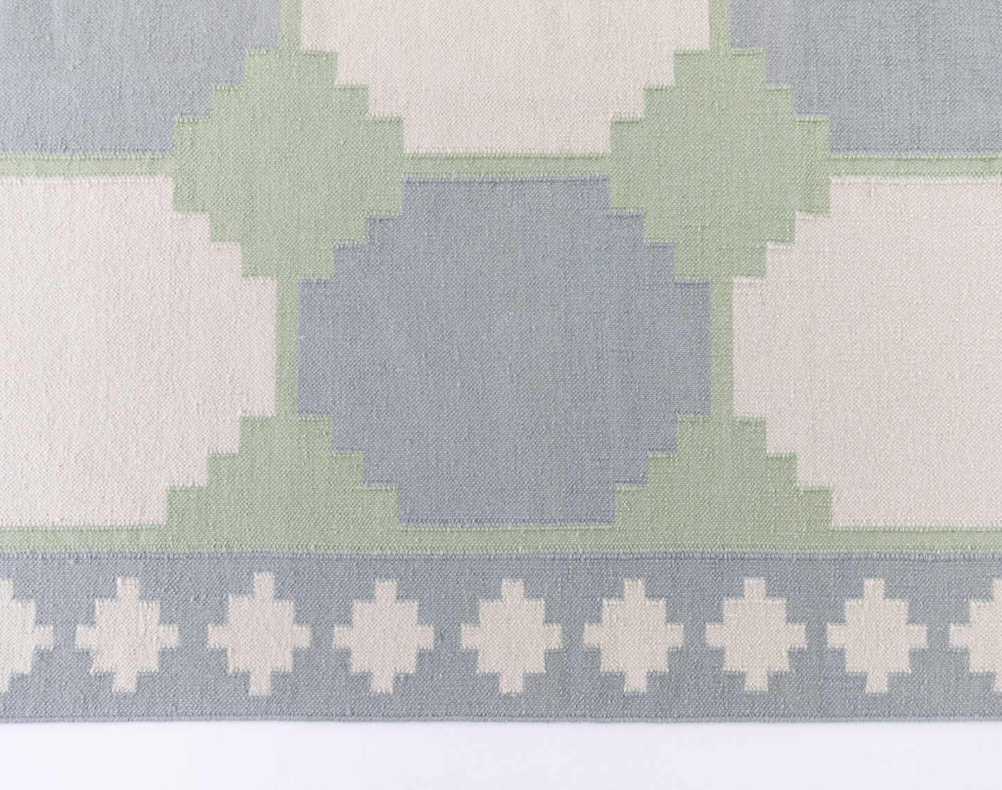 Geometric Flatweave Rug featuring an oversized geometric pattern in soft blue, sage green, and ivory.