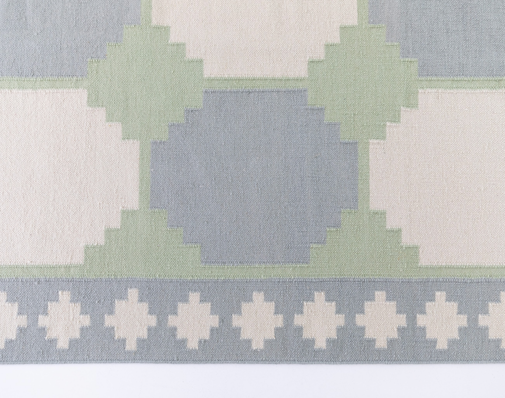 Geometric Flatweave Rug featuring an oversized geometric pattern in soft blue, sage green, and ivory.