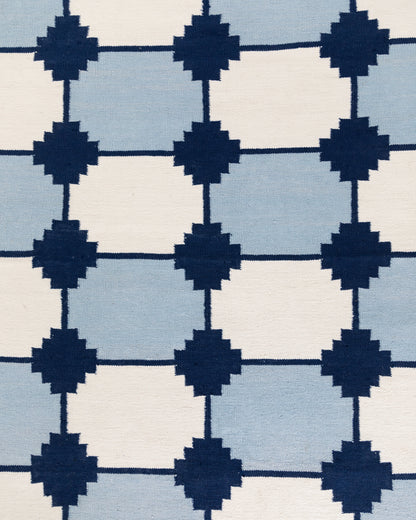 Navy and white wool flatweave dhurrie rug with oversized blue geometric pattern