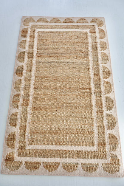 Handwoven jute and wool rug in natural tones with a soft blush pink scalloped edge border – Pink Palm Scalloped Edge Rug by Locust Lane Rugs