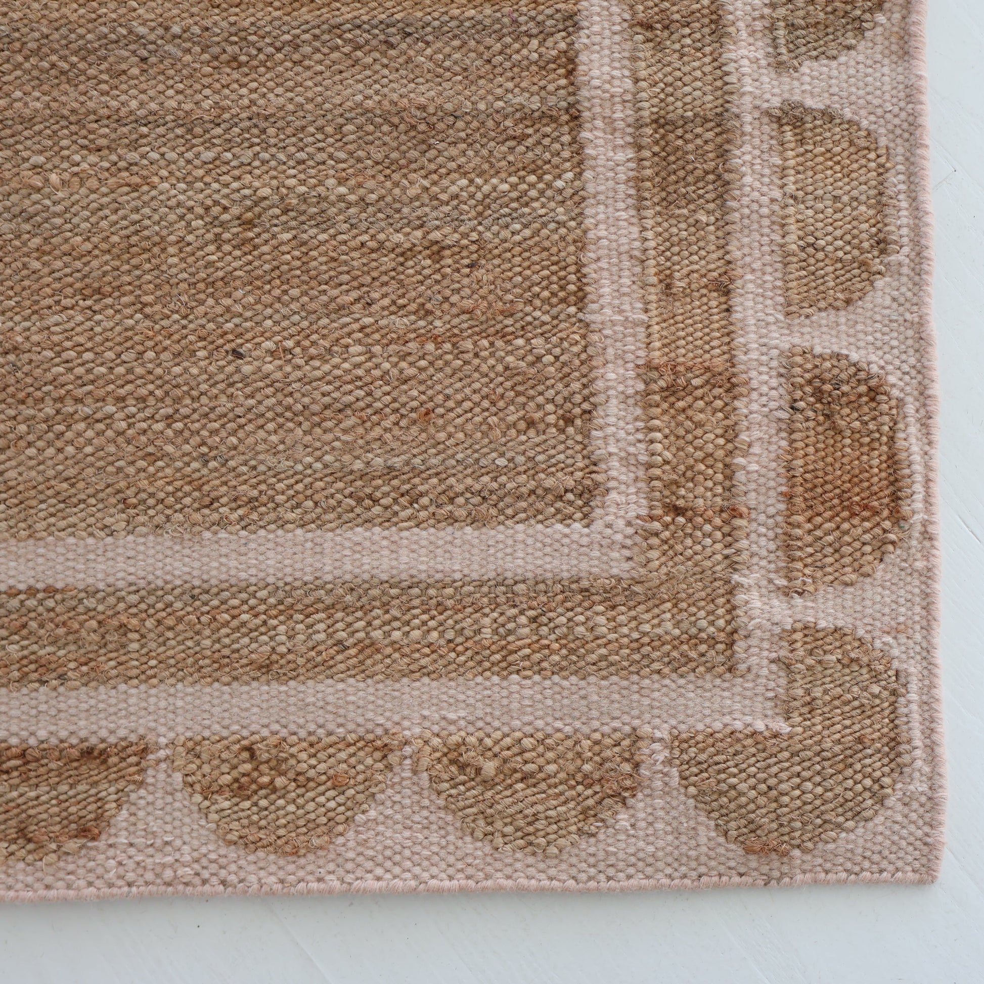 Handwoven jute and wool rug in natural tones with a soft blush pink scalloped edge border – Pink Palm Scalloped Edge Rug by Locust Lane Rugs