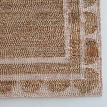 Handwoven jute and wool rug in natural tones with a soft blush pink scalloped edge border – Pink Palm Scalloped Edge Rug by Locust Lane Rugs