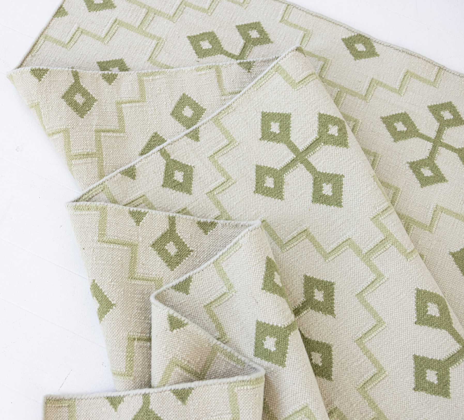 Folded Pistachio Green Geometric Flatweave Rug featuring its reversible handwoven construction.