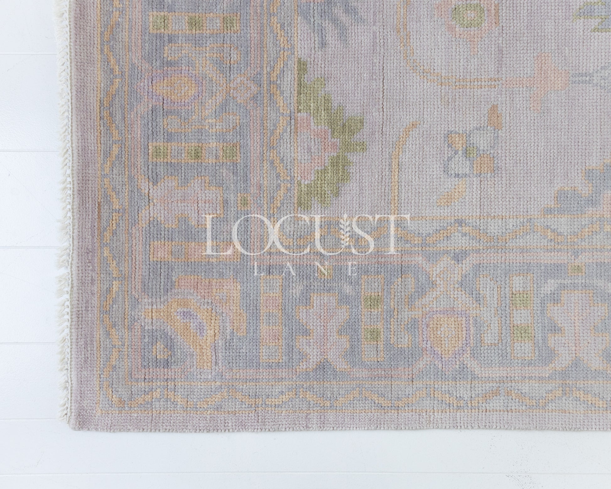 Hand-knotted wool rug in soft lavender and blush tones with sage and peach accents. The Rose Rug from Locust Lane features a delicate floral-inspired pattern that blends modern pastel hues with timeless craftsmanship.