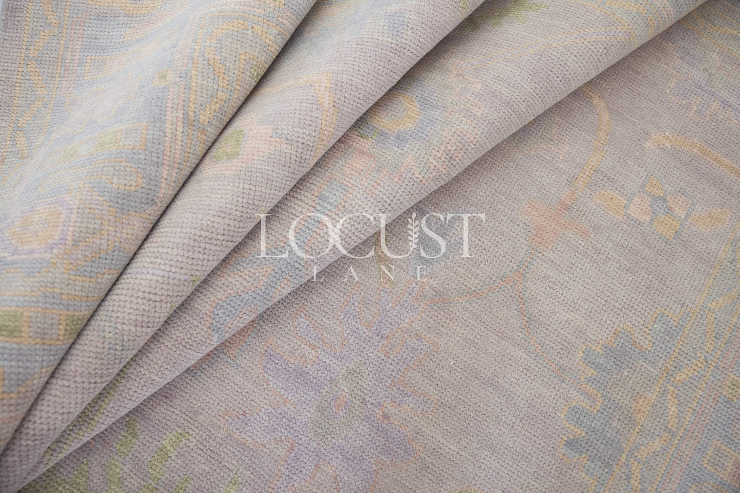 Hand-knotted wool rug in soft lavender and blush tones with sage and peach accents. The Rose Rug from Locust Lane features a delicate floral-inspired pattern that blends modern pastel hues with timeless craftsmanship.