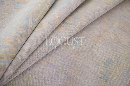 Hand-knotted wool rug in soft lavender and blush tones with sage and peach accents. The Rose Rug from Locust Lane features a delicate floral-inspired pattern that blends modern pastel hues with timeless craftsmanship.