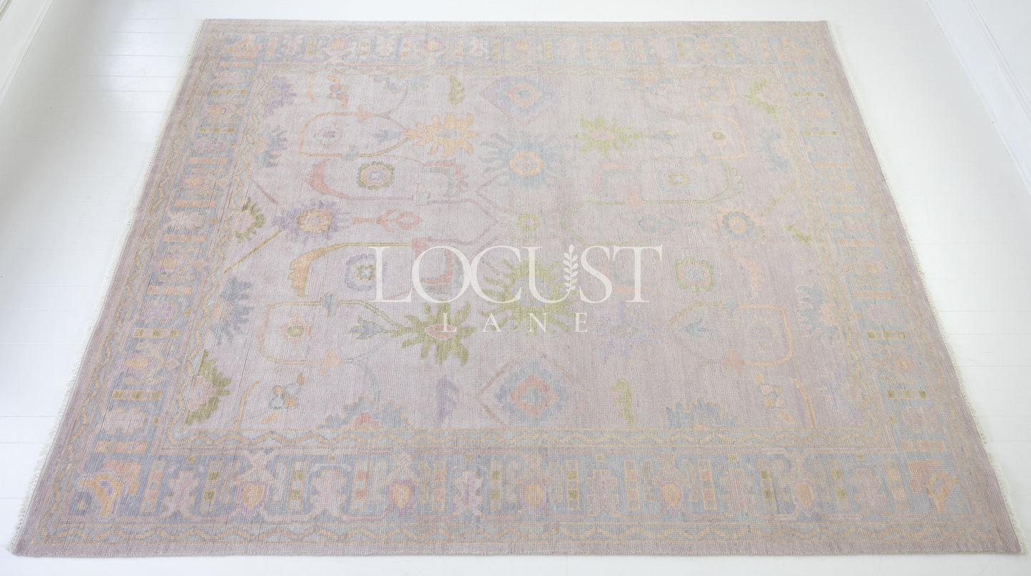 Hand-knotted wool rug in soft lavender and blush tones with sage and peach accents. The Rose Rug from Locust Lane features a delicate floral-inspired pattern that blends modern pastel hues with timeless craftsmanship.