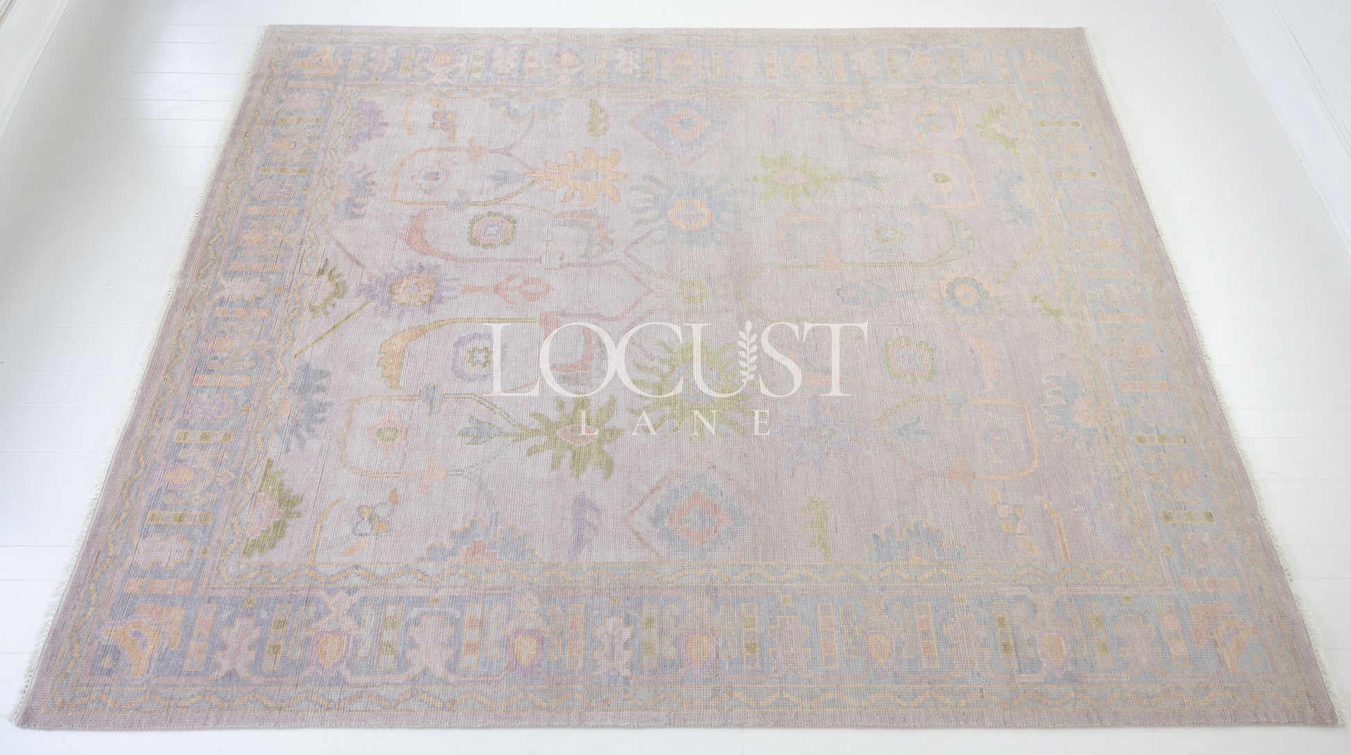 Hand-knotted wool rug in soft lavender and blush tones with sage and peach accents. The Rose Rug from Locust Lane features a delicate floral-inspired pattern that blends modern pastel hues with timeless craftsmanship.