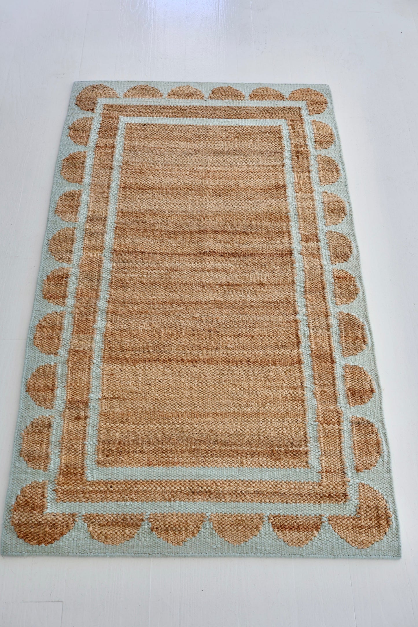 Handwoven jute and wool rug in natural tones with a sea blue scalloped border – Sea Cliff Blue Scalloped Edge Rug by Locust Lane Rugs
