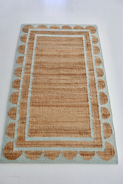 Handwoven jute and wool rug in natural tones with a sea blue scalloped border – Sea Cliff Blue Scalloped Edge Rug by Locust Lane Rugs