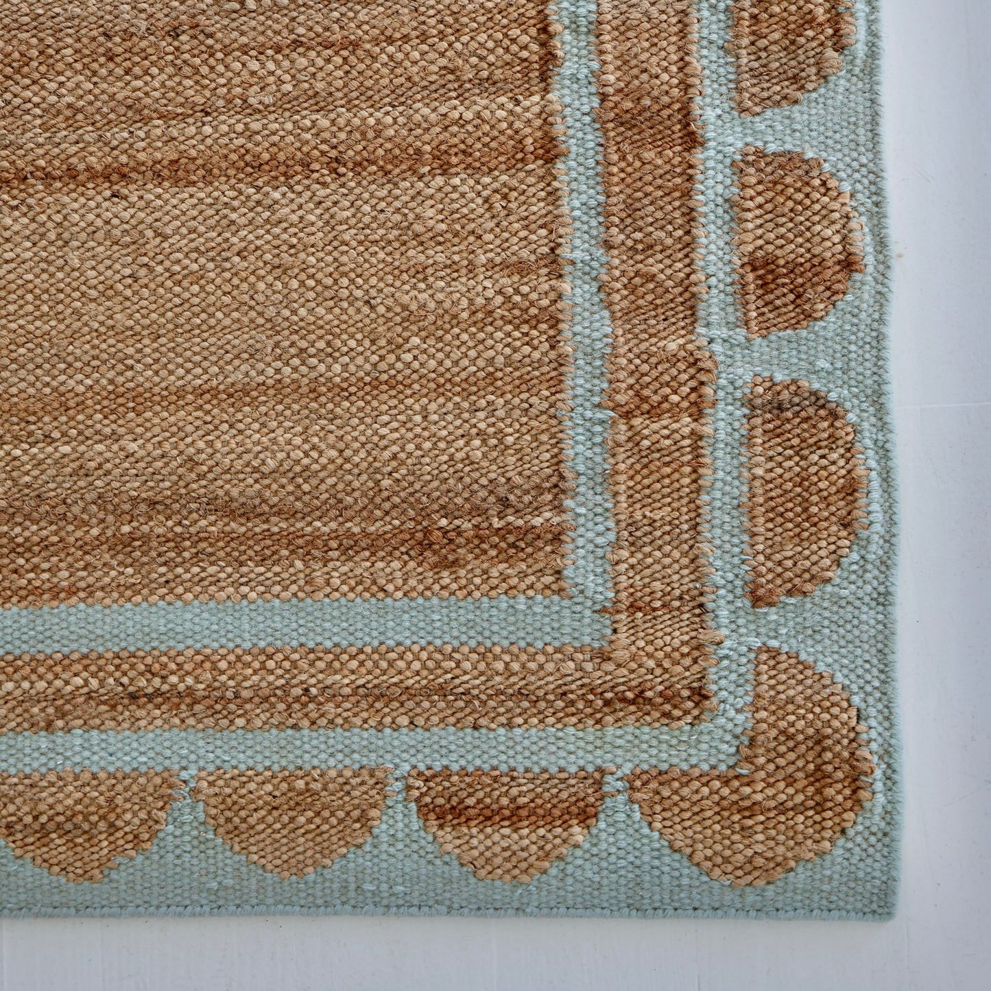 Handwoven jute and wool rug in natural tones with a sea blue scalloped border – Sea Cliff Blue Scalloped Edge Rug by Locust Lane Rugs