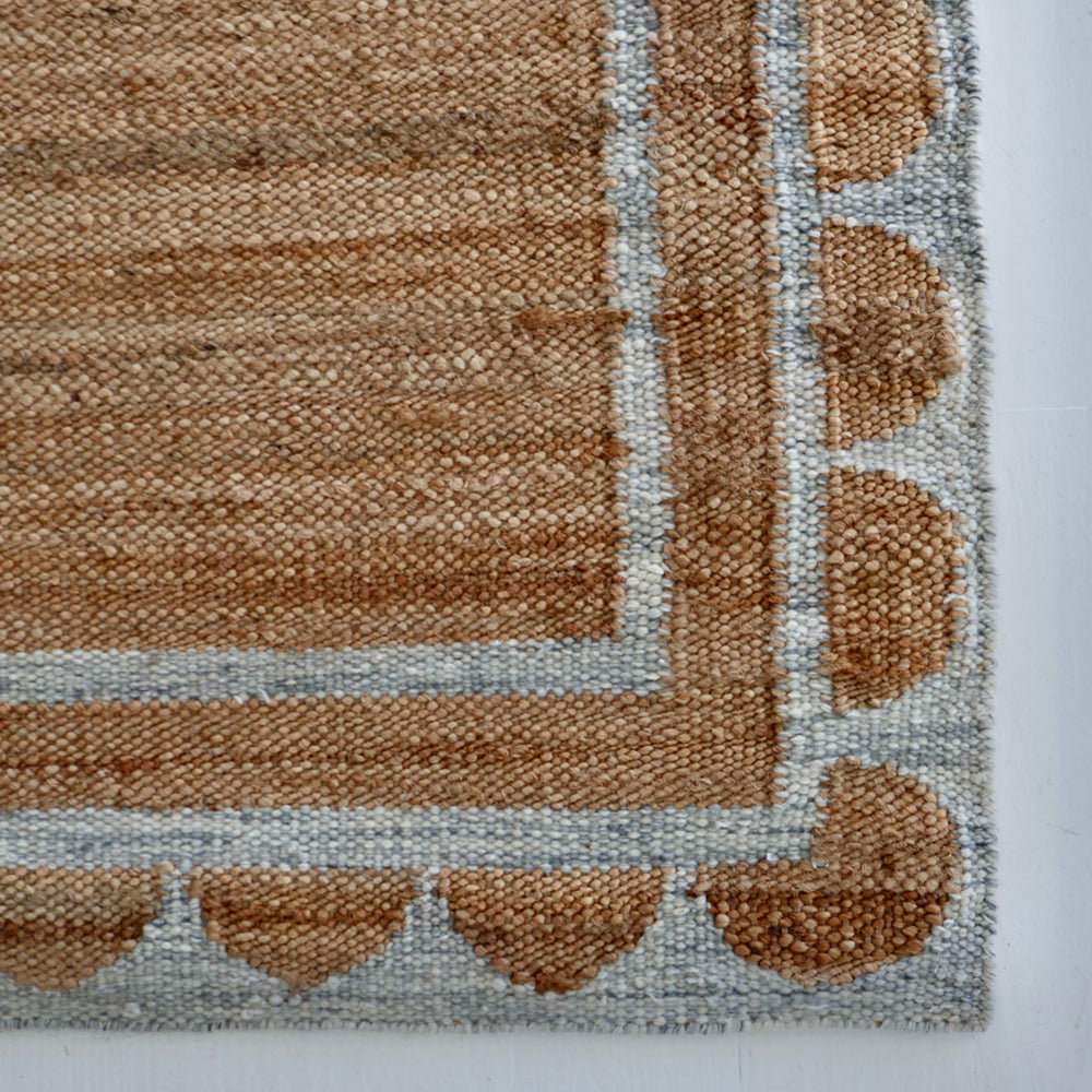 Handwoven jute and wool rug in natural tones with a stone-blue scalloped border – Stone Blue Scalloped Edge Rug by Locust Lane Rugs